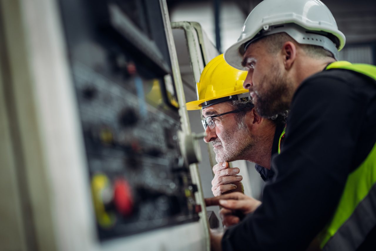 mechanical engineering team operating machinery in a manufacturing workshop